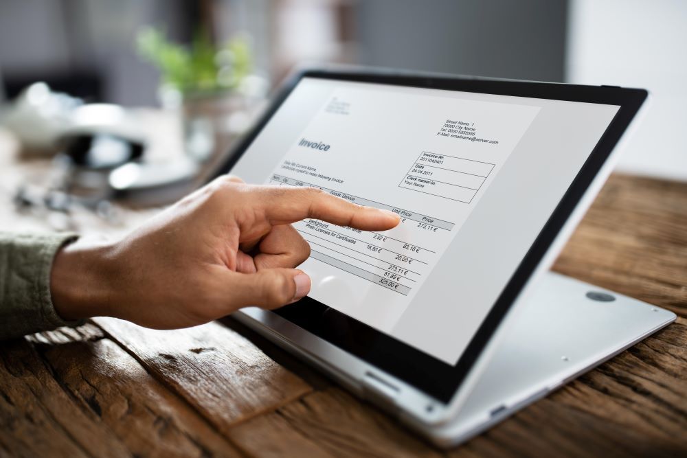 Index d'une main montrant le prix d'un facture sur un ordinateur